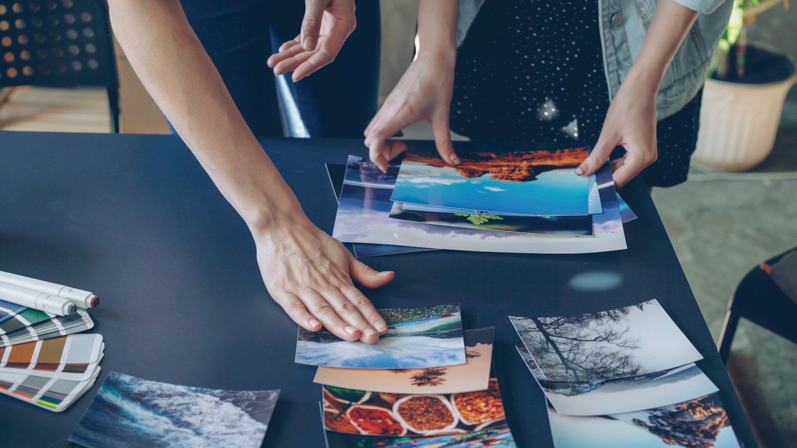 Hands arranging photographs and design materials on a table